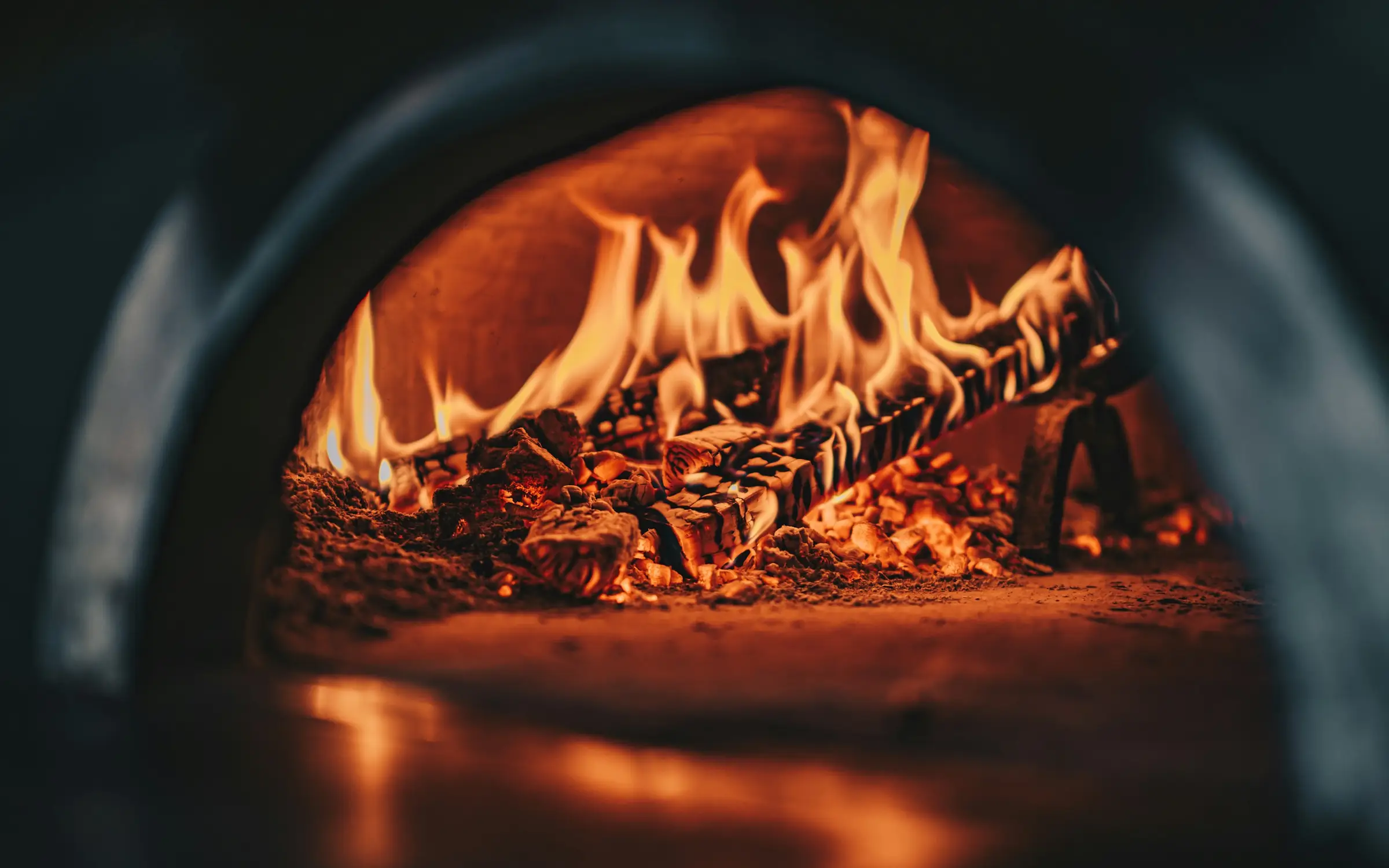 Flames curling along the back wall of the wood-burning hearth at Ember & Fork