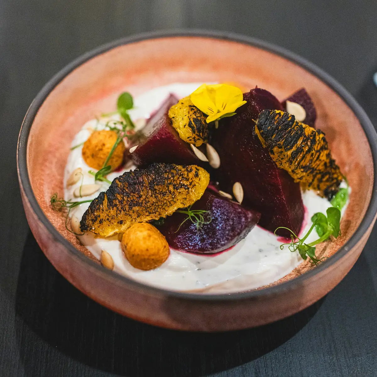 A bowl of charred vegetables and grains, photographed from above