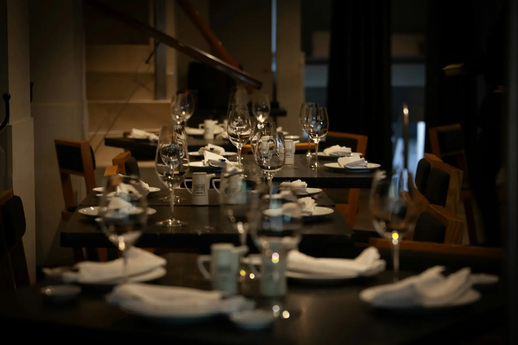A long table laid for service in a dark dining room, lit by candles
